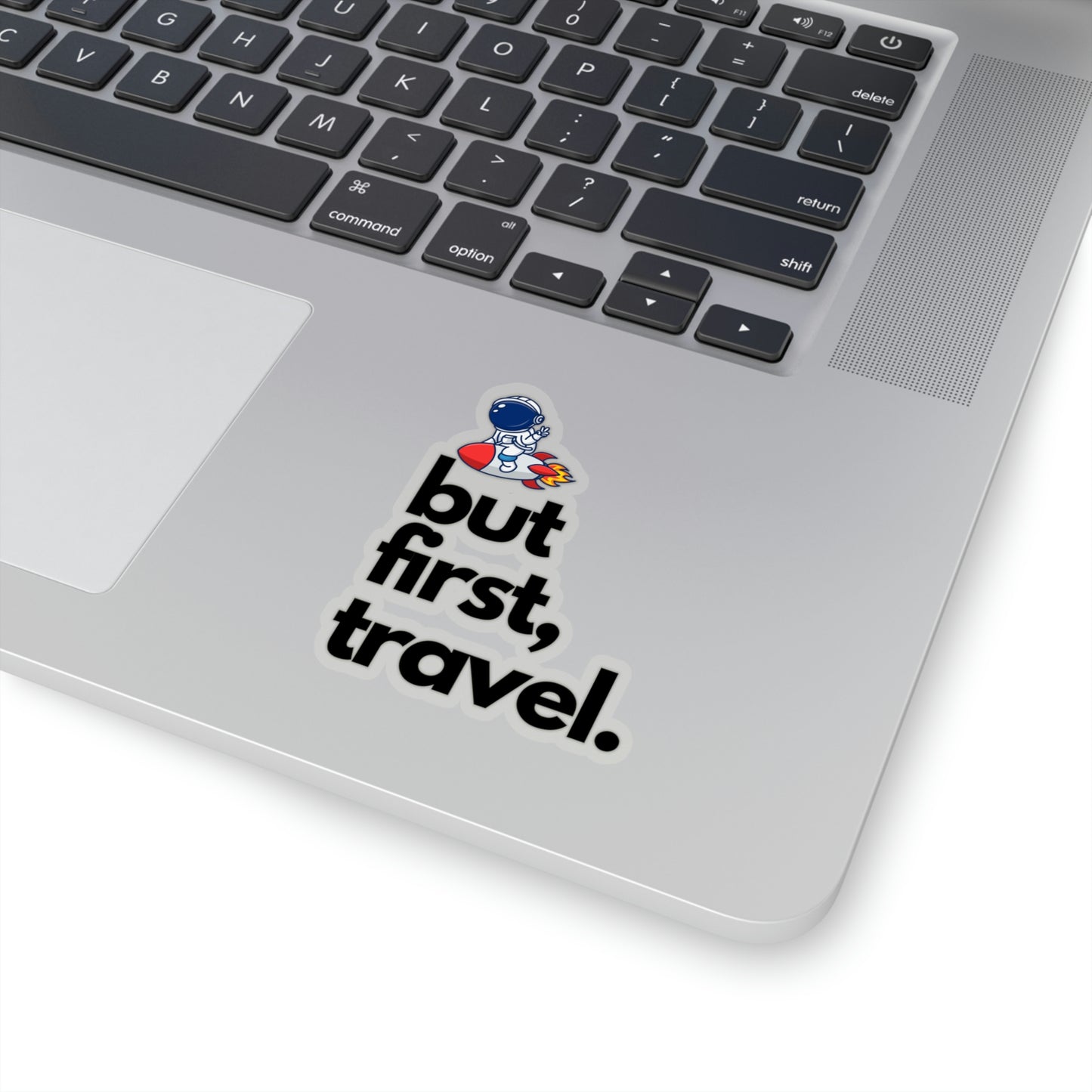 Large vinyl sticker on a laptop featuring words "but first travel".
