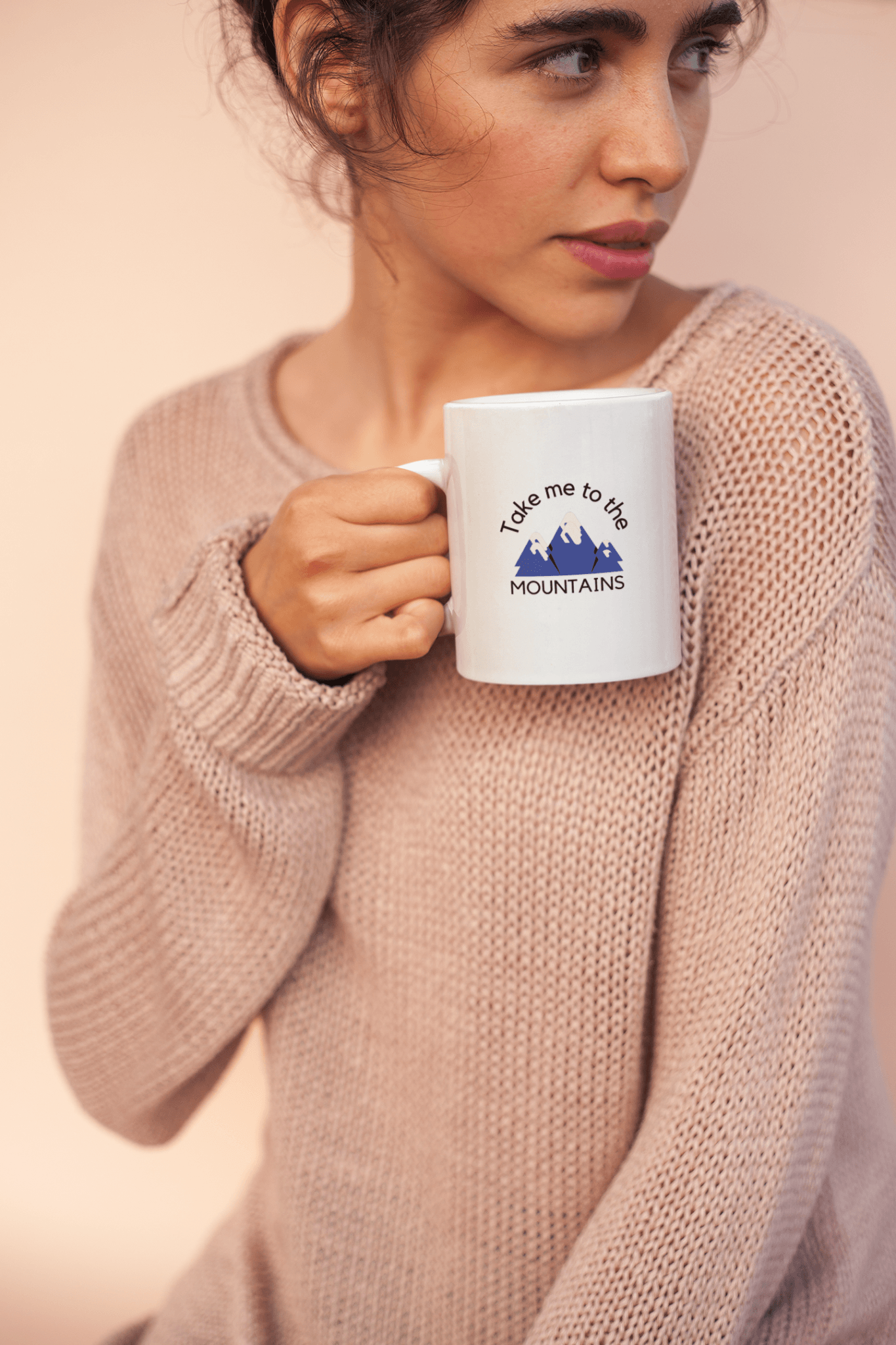 Woman wearing a cozy sweater holding a white ceramic coffee cup.