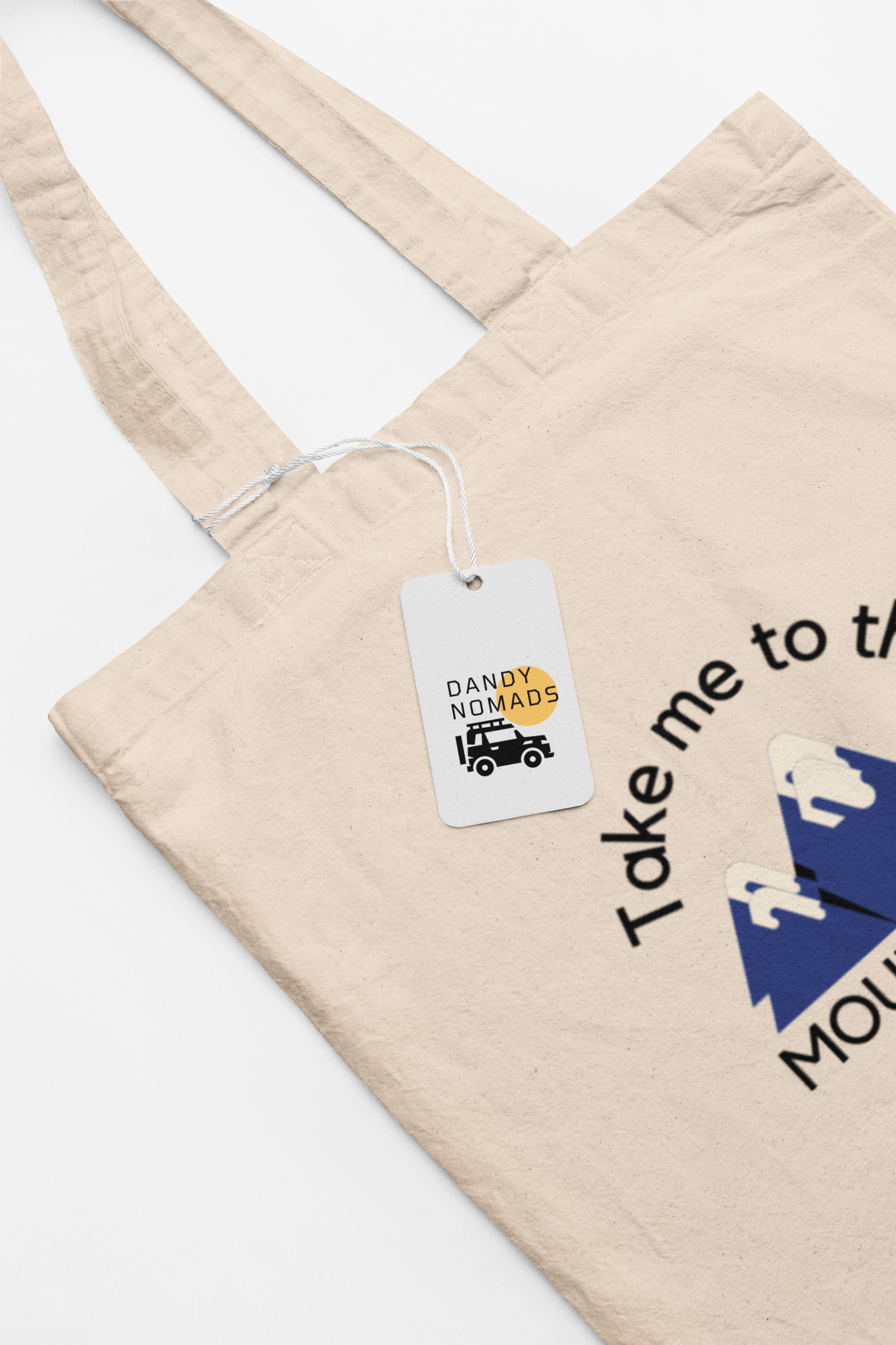 Canvas tote bag on white background, featuring text "take me to the mountains"